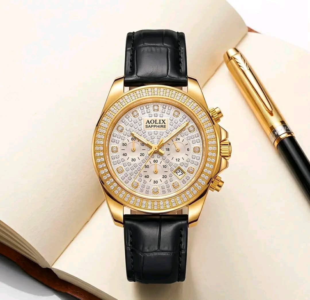 Gold-tone watch with crystal-style dial details and black leather-look strap