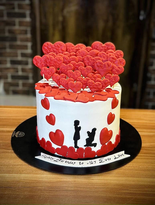 Elegant white birthday cake with flowing icing and floral decoration
