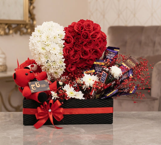 Heart-shaped red rose arrangement with pink heart balloons