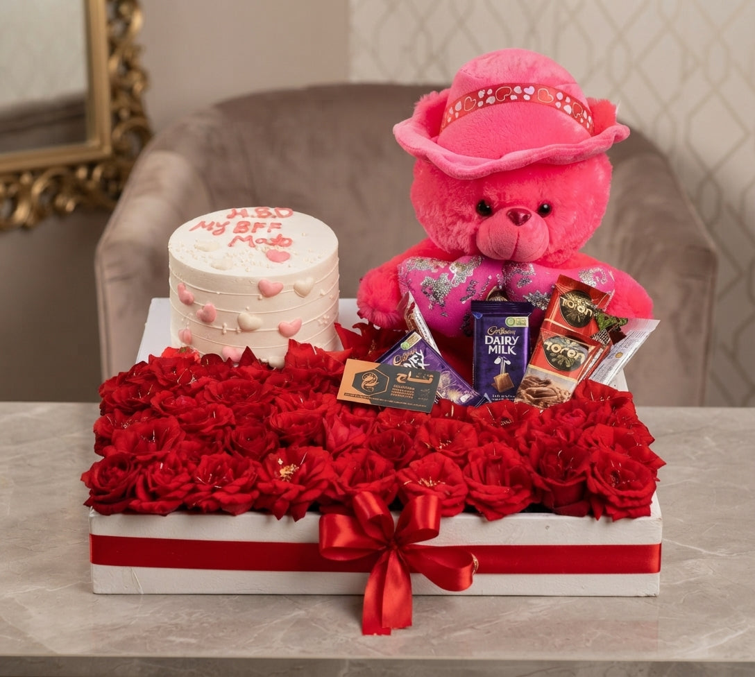 Red rose gift arrangement with pink teddy bear, cake, and chocolates